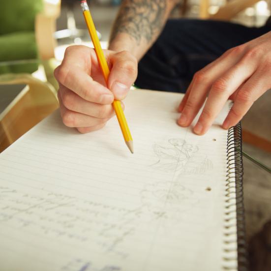 Person, der skriver med blyant på en notesblog.