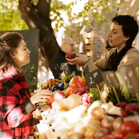 To kvinder, der taler sammen på et marked.